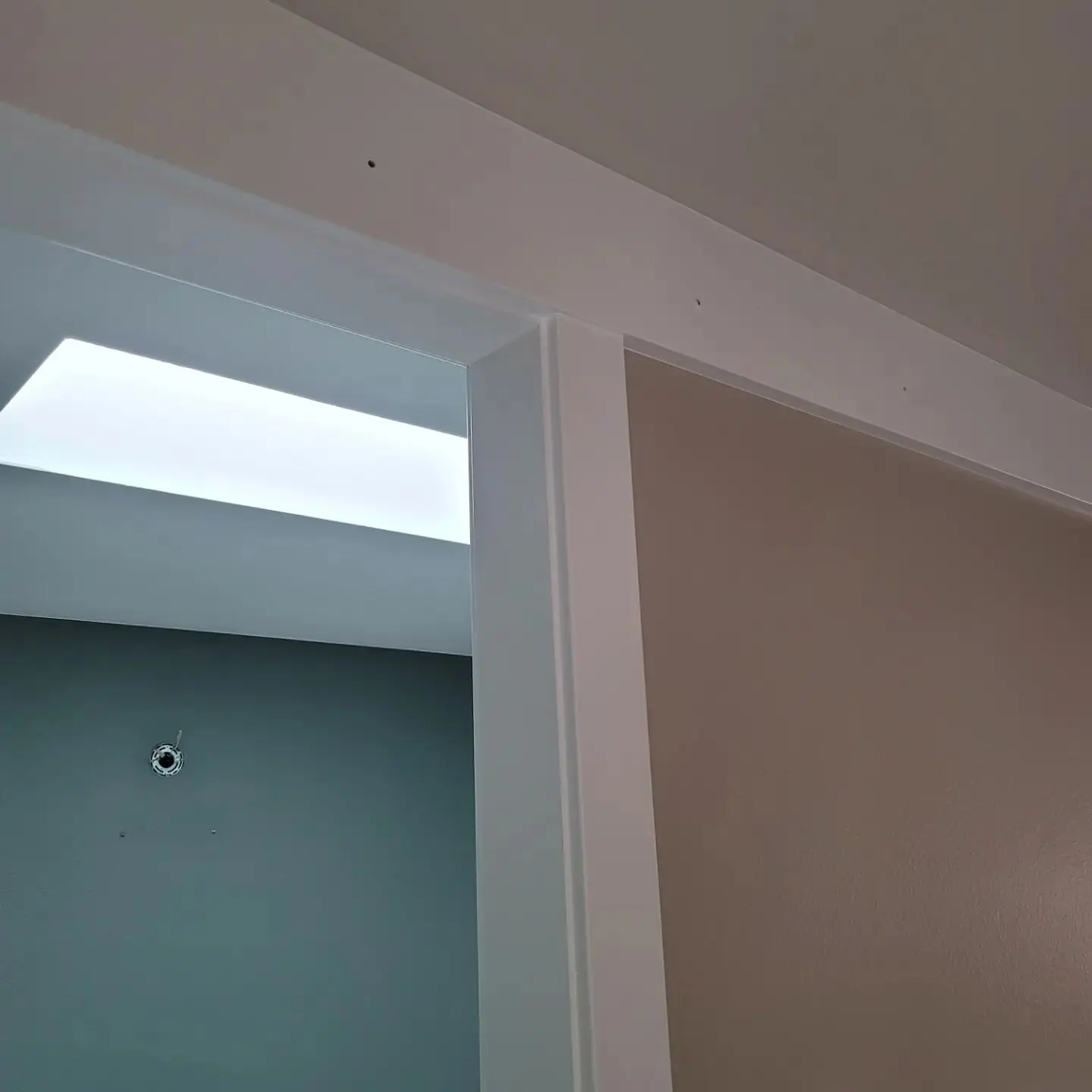 Detail shot of professional white header trim paint against a neutral beige wall.