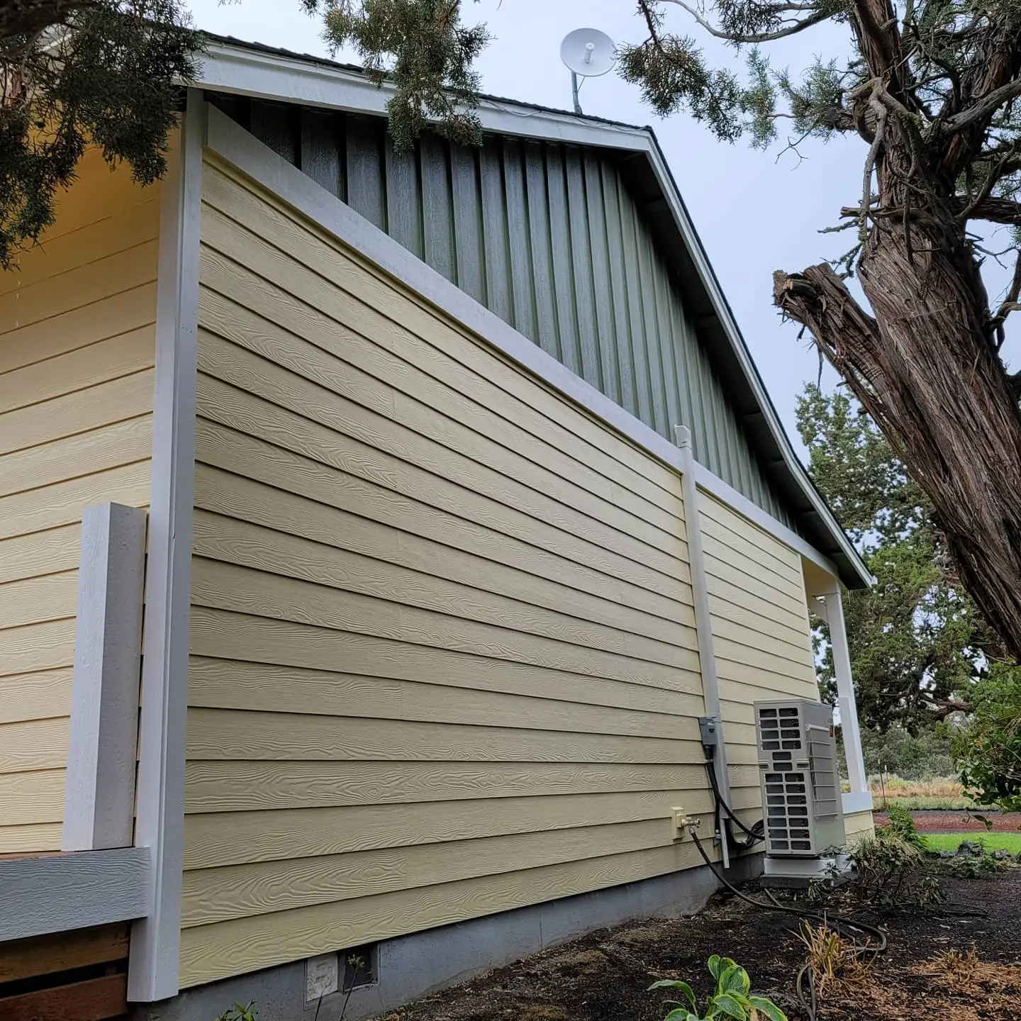 High-quality exterior paint finish on a ranch-style home in Alfalfa, OR, featuring white trim and yellow siding.