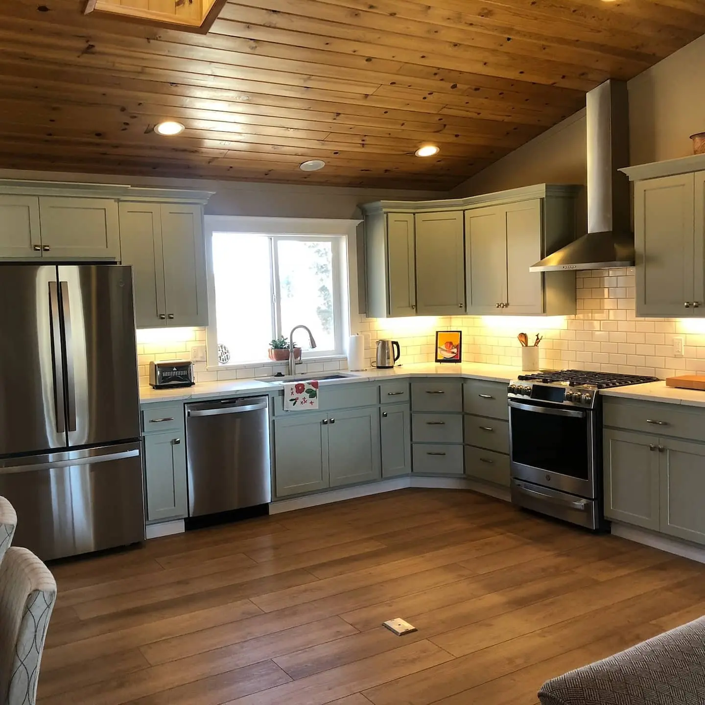 After view of a kitchen in Alfalfa featuring sage green painted cabinets and white subway tile