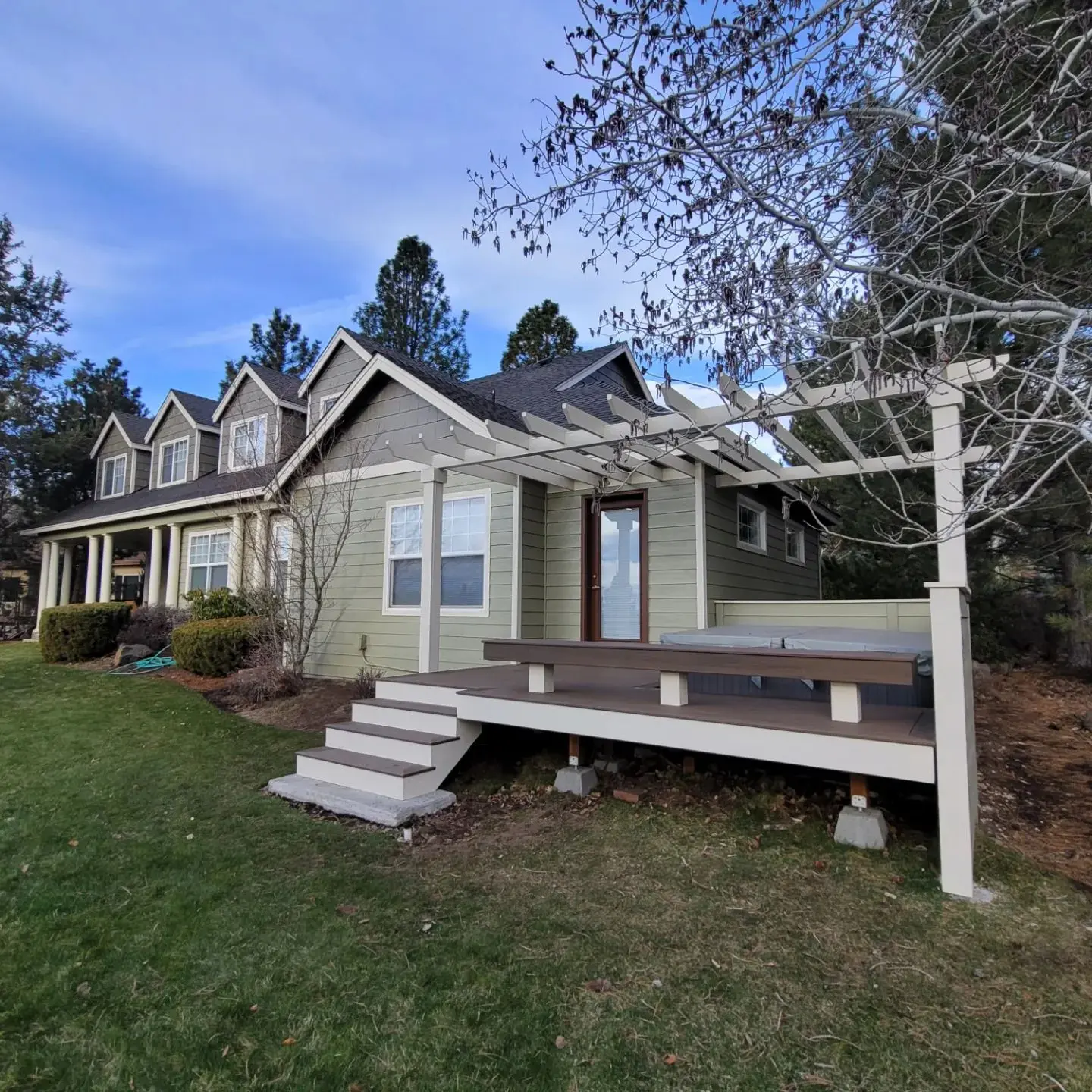 Rear deck area in Bend with a white pergola and freshly stained multi-level wood decking.