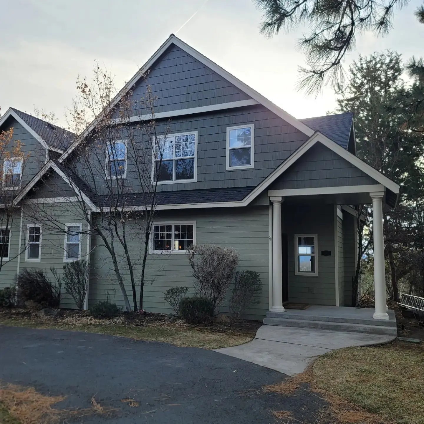 Wide view of a remodeled Bend home featuring sage green siding and slate blue cedar shingles.