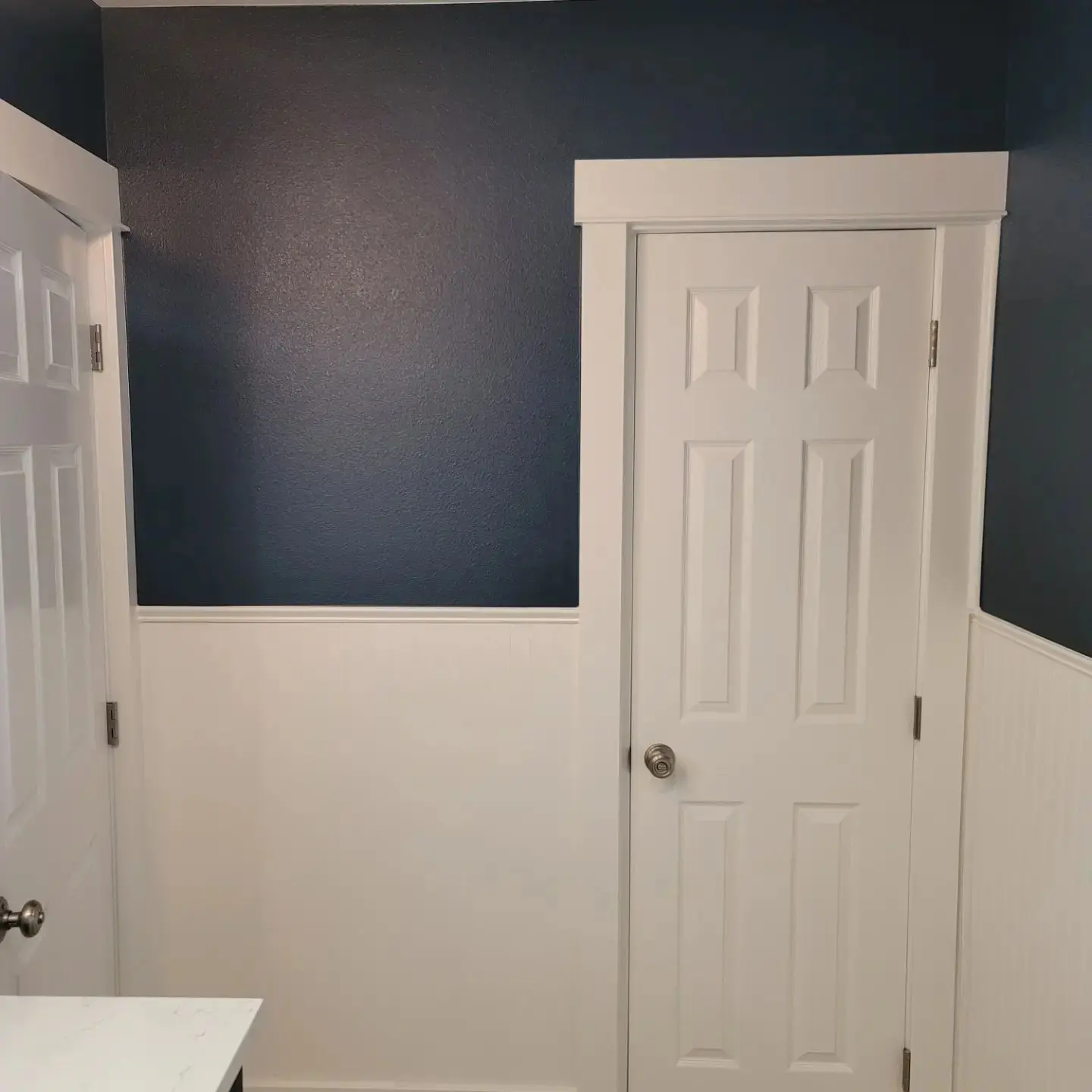 Close-up of a professionally painted navy blue accent wall and white door trim in a Bend home.