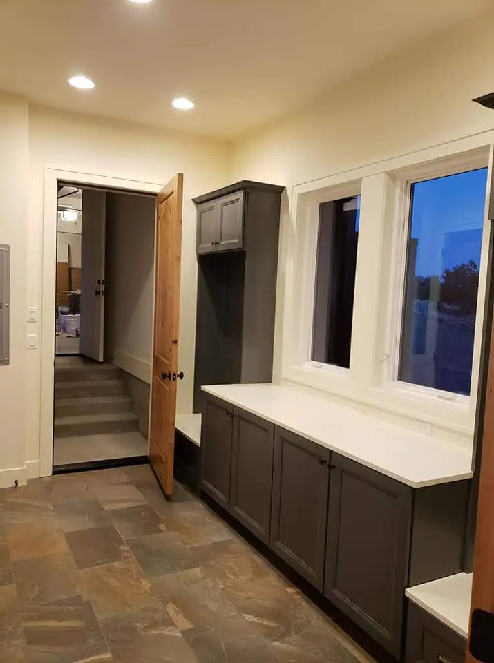 Professional cabinet painting for a mudroom featuring deep grey tones and white countertops.