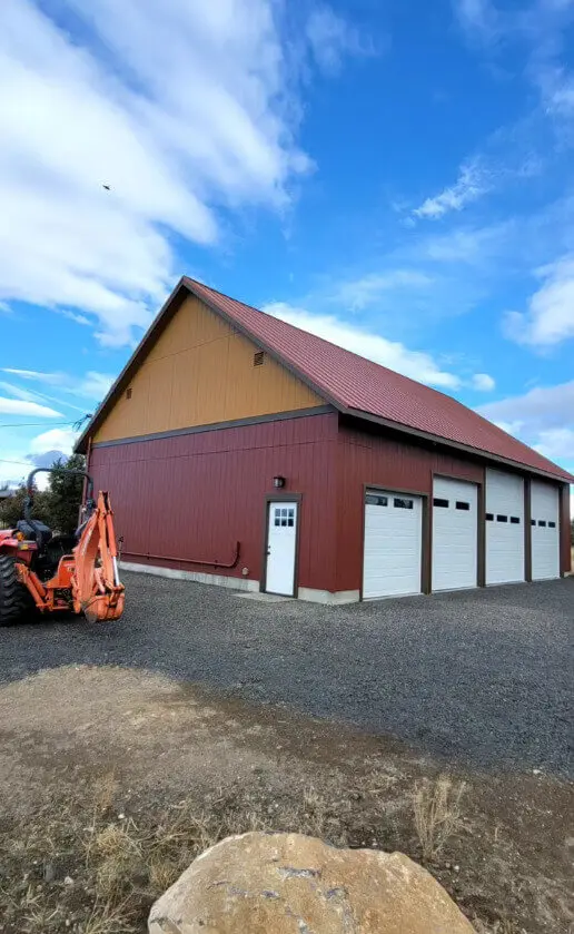 A fully finished exterior paint project on a large rural shop with white accent doors.