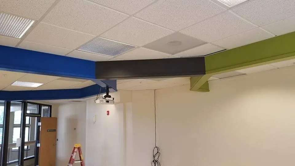 Multi-colored ceiling beams in blue, black, and lime green showcasing custom commercial accent painting