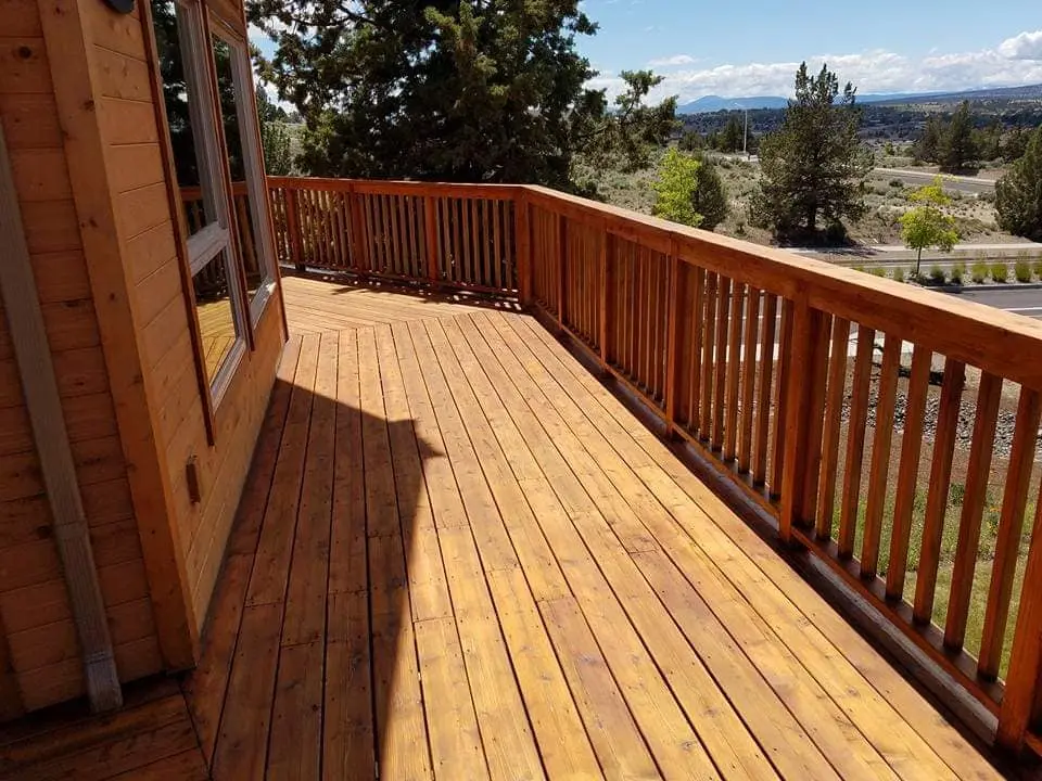 Looking down a long wooden deck railing with a uniform, protective stain application.