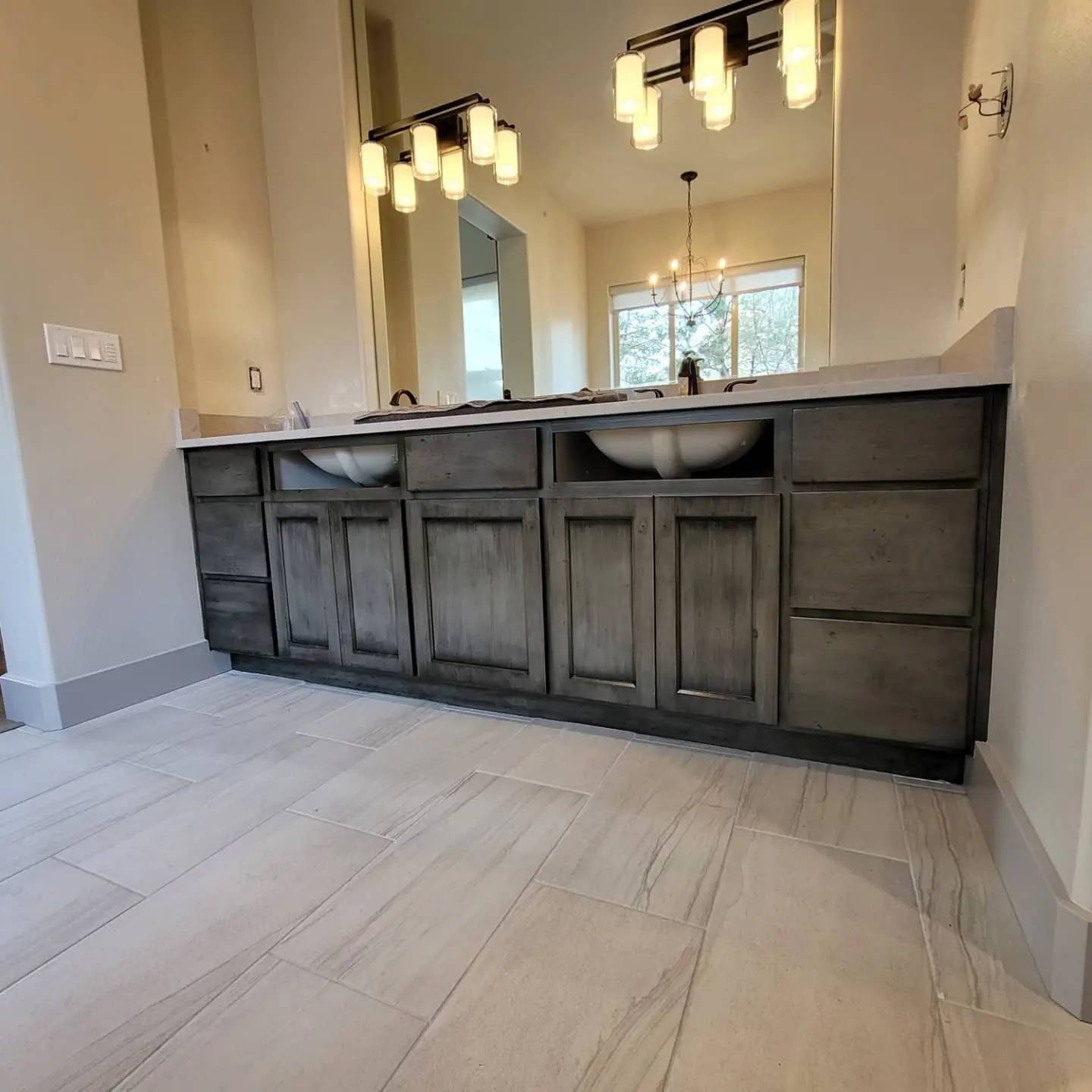 Wide view of custom glazed bathroom cabinetry and light tile flooring in a Redmond home.