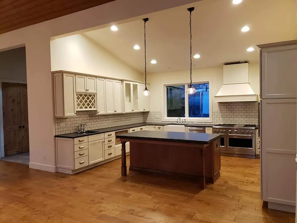Modern kitchen with cream-colored cabinets, subway tile backsplash, and dark wood island in Brasada Ranch.