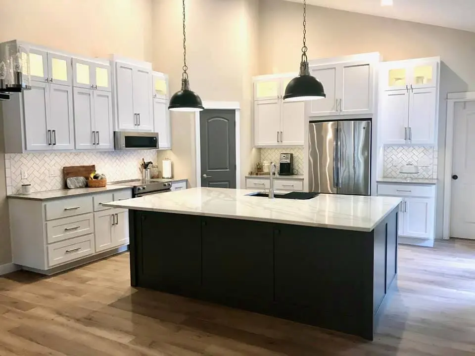 Finished modern kitchen in Central Oregon with white upper cabinets and a large charcoal grey island.