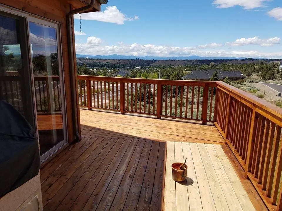 Side-by-side comparison showing a weathered wood deck next to a section with new professional stain.