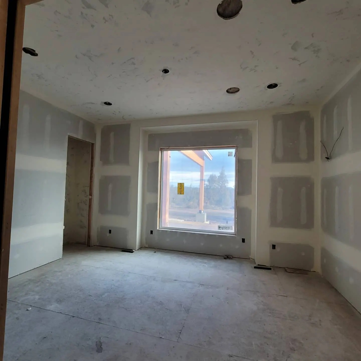 Interior bedroom view showing completed drywall around large windows in Eagle Crest new construction.