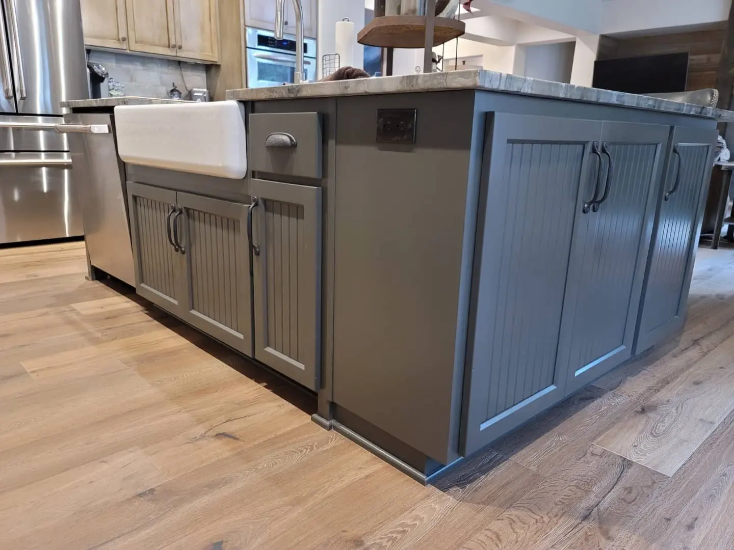 Close-up of a charcoal grey refinished kitchen island featuring a white farmhouse sink.