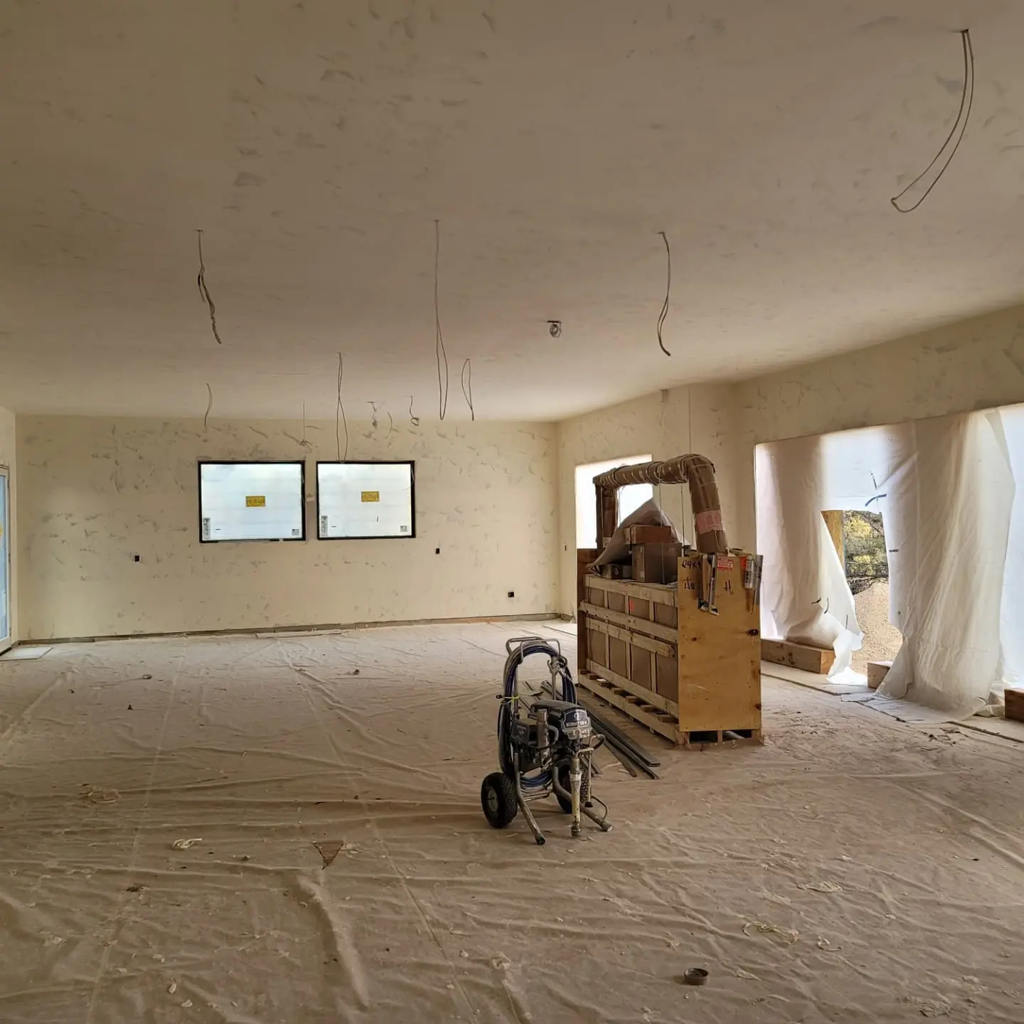 Professional airless paint sprayer set up in a large open-concept room for a new construction project in Eagle Crest.