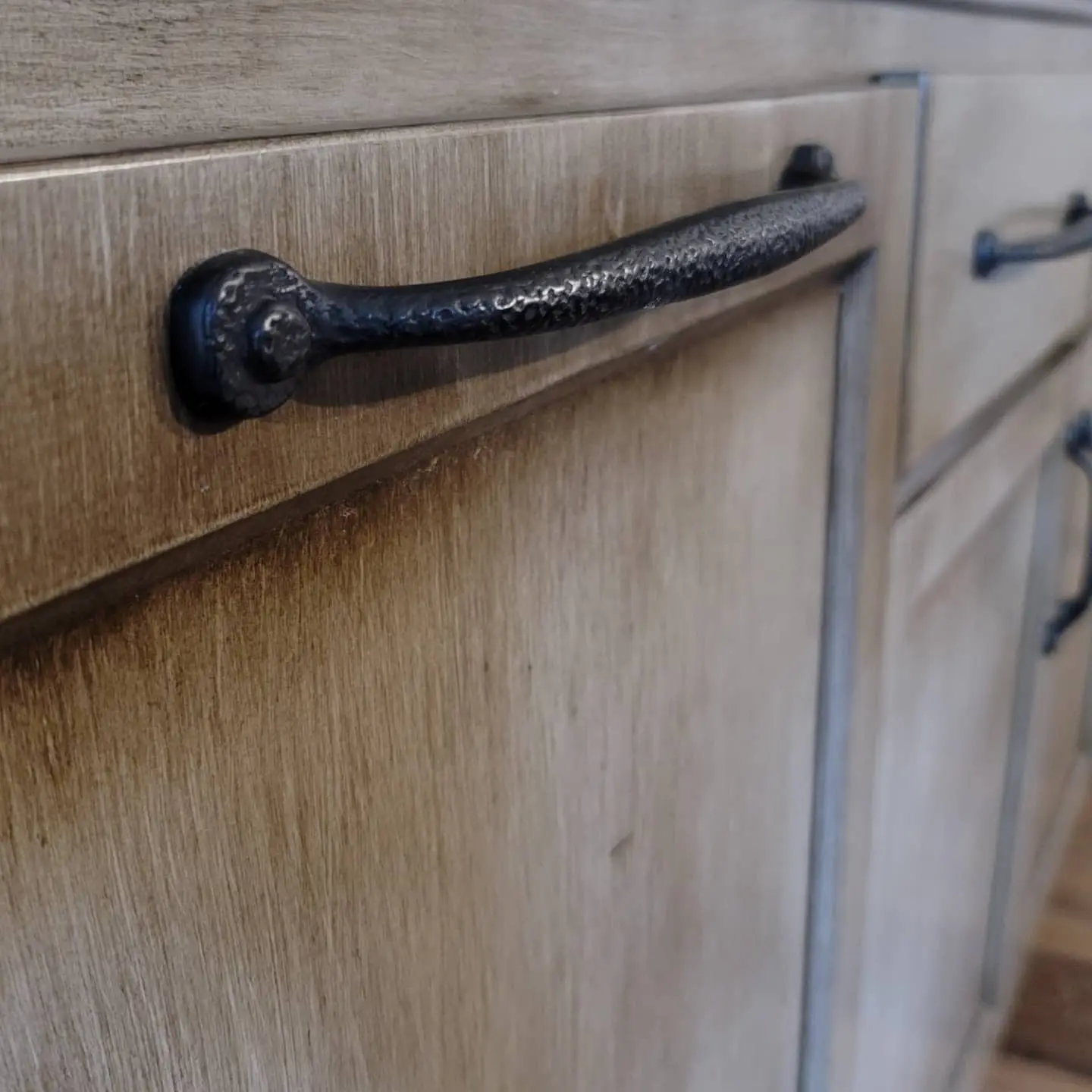Close-up of hammered rustic iron hardware on refinished glazed wood cabinets in Eagle Crest.