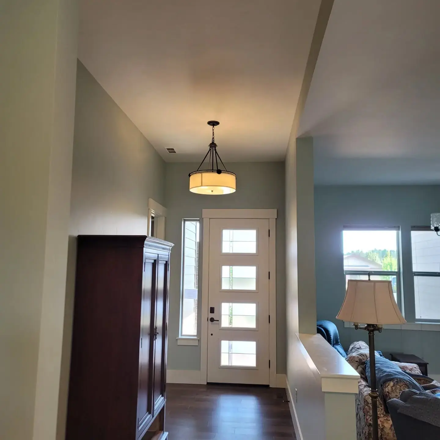 A bright, freshly painted entryway with a white modern front door and clean white baseboard trim.