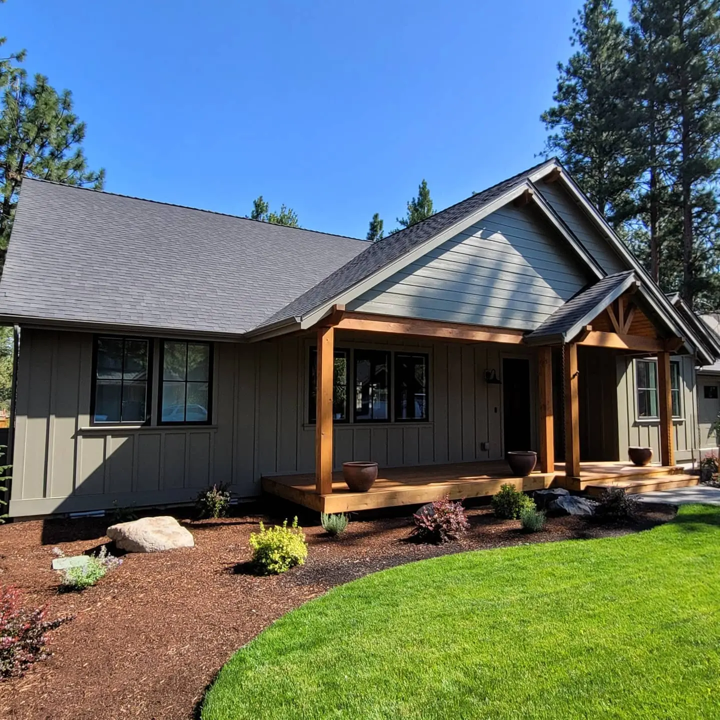 Full front view of a Sisters home painted with Miller Evolution in an olive-green tone with black door accents.