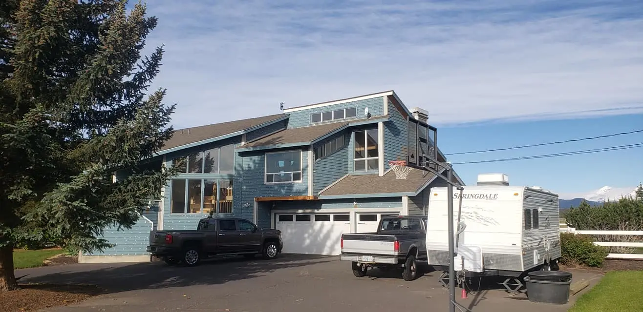 Front profile of a large home during the siding restoration and preparation phase.