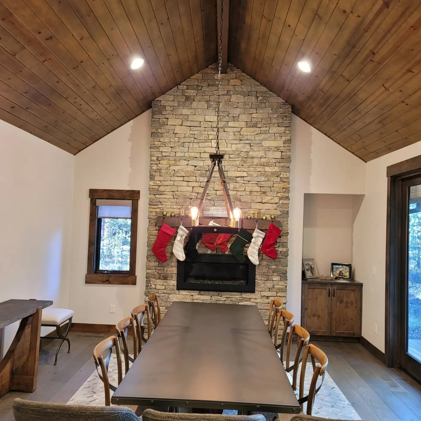 High-ceilinged dining room in Sunriver with a massive stone fireplace and matching custom wood cabinetry.