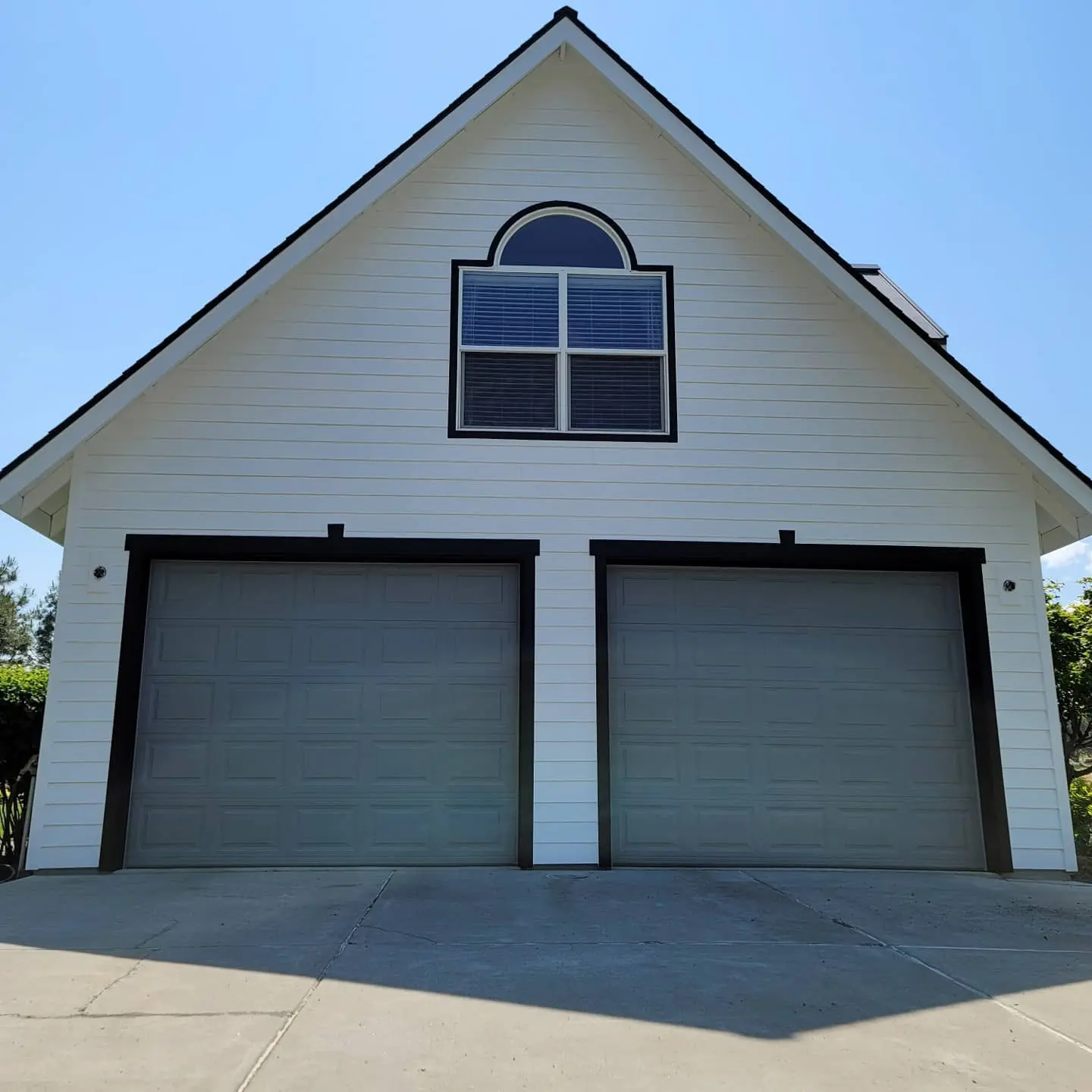 Two-car garage in Bend featuring grey doors with sharp black trim borders against white siding.