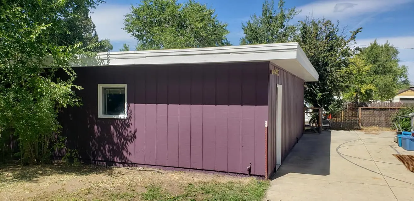 Rear exterior wall of a garage showing crisp paint lines around the window and roofline.