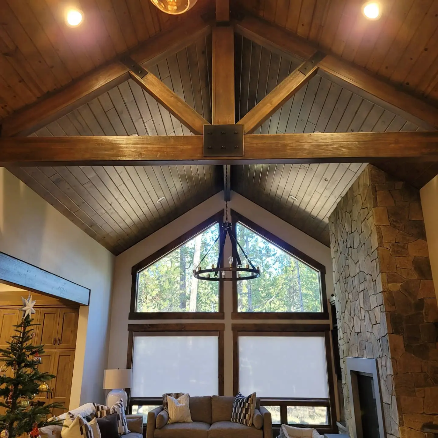 Expansive great room in Sunriver featuring a vaulted wood ceiling, timber trusses, and a floor-to-ceiling stone fireplace.