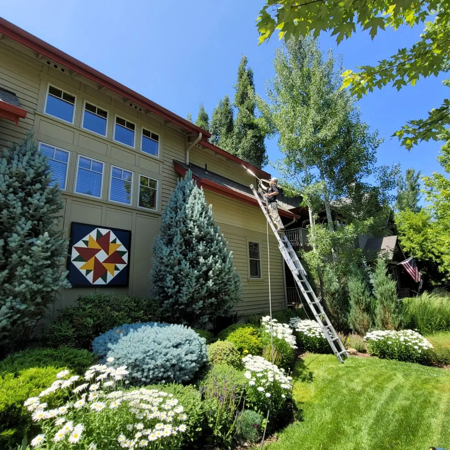 Using an extension ladder to carefully prep the upper gables of a large residential home in Sisters.