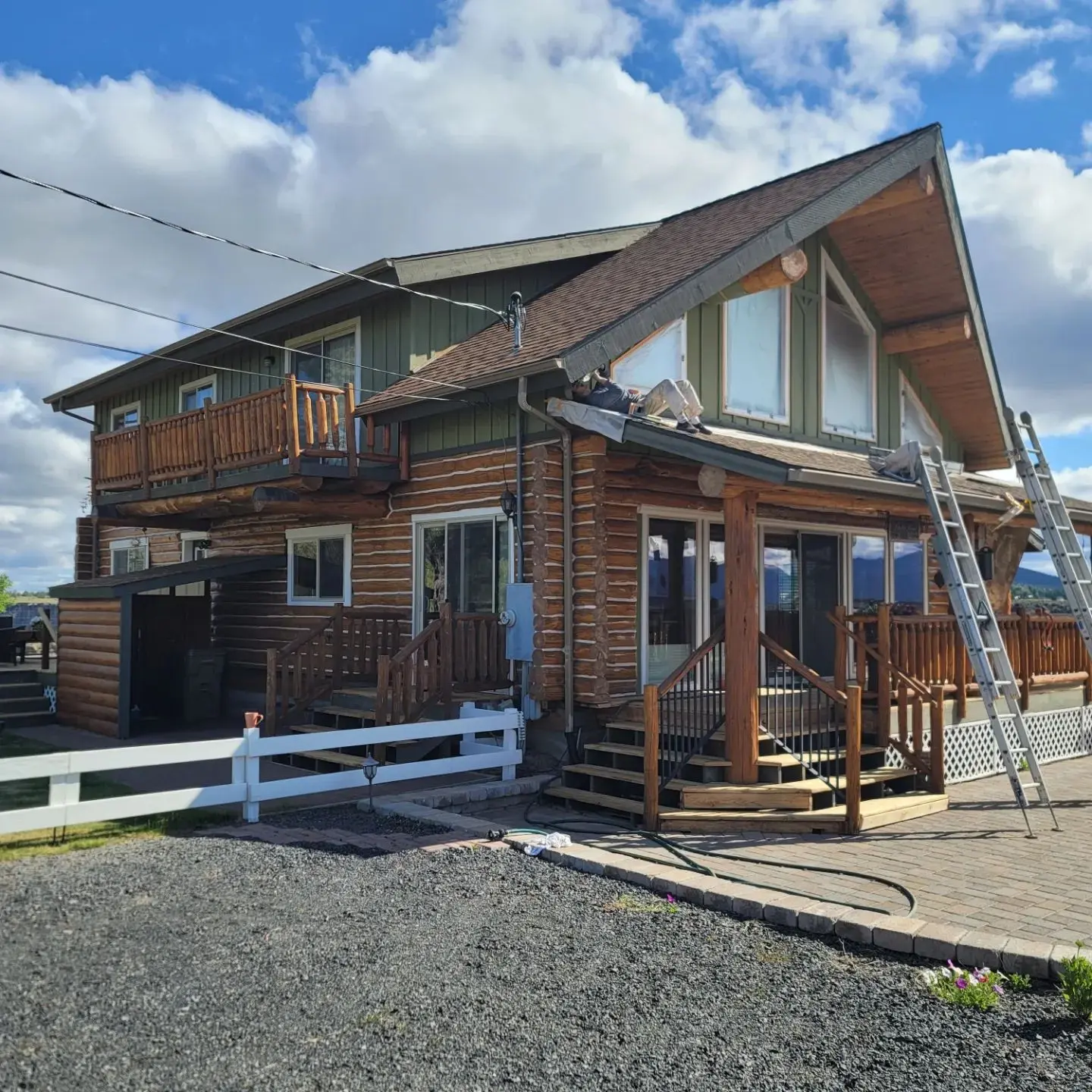 Professional painters using extension ladders to mask and prep a log home exterior in Central Oregon.
