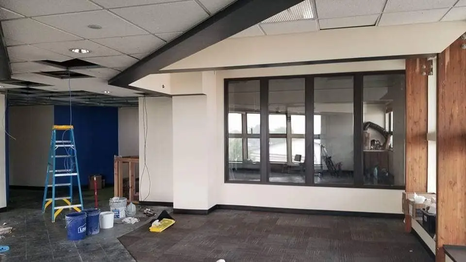 Large open interior space featuring a vibrant blue accent wall in progress alongside neutral painted surfaces