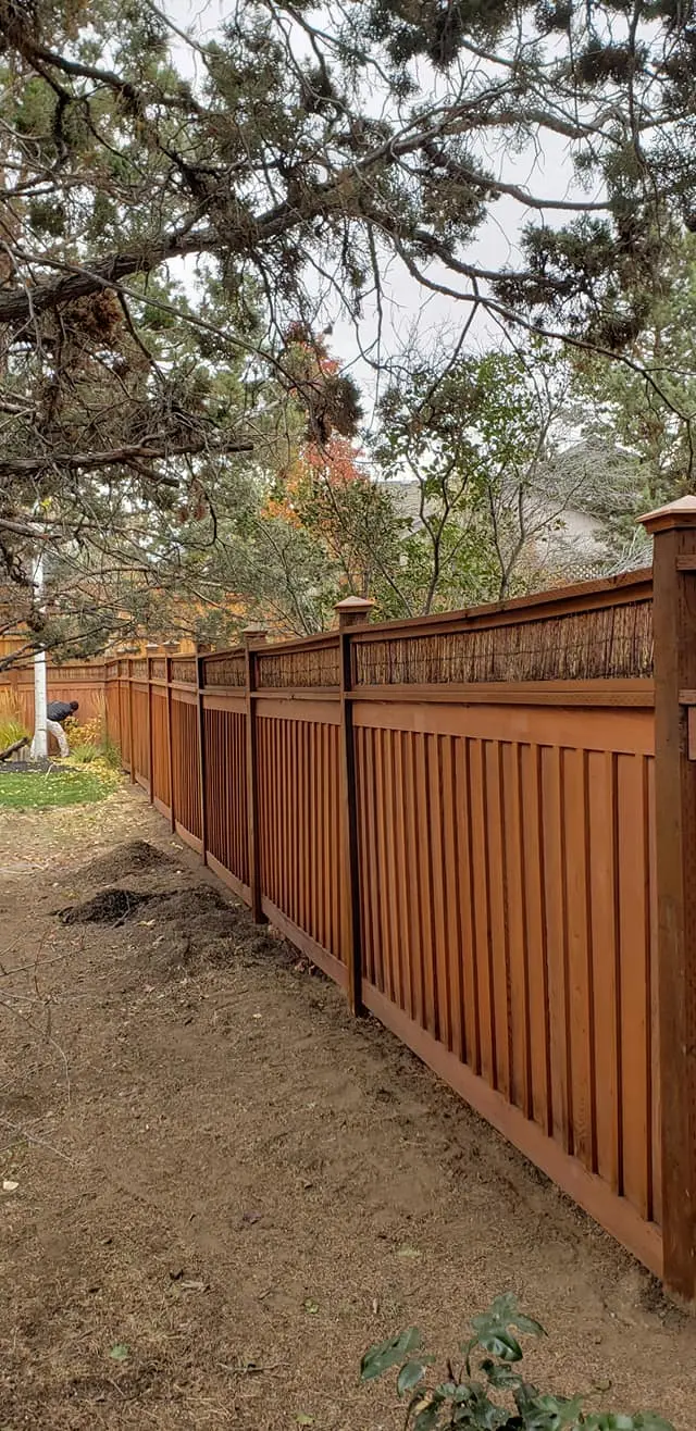 Perspective view of a long wooden fence showcasing consistent stain coverage