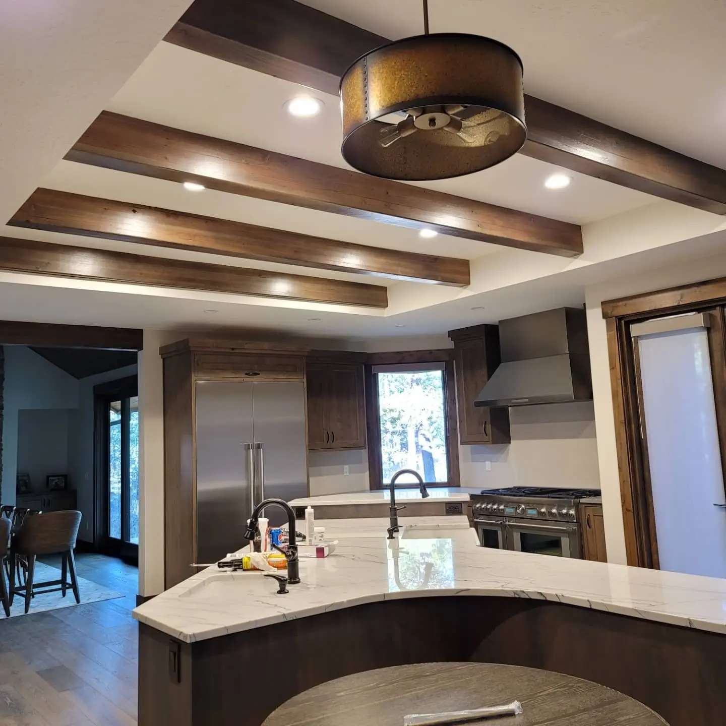 Sunriver custom kitchen featuring a large dark-stained island, white quartz countertops, and industrial pendant lights.