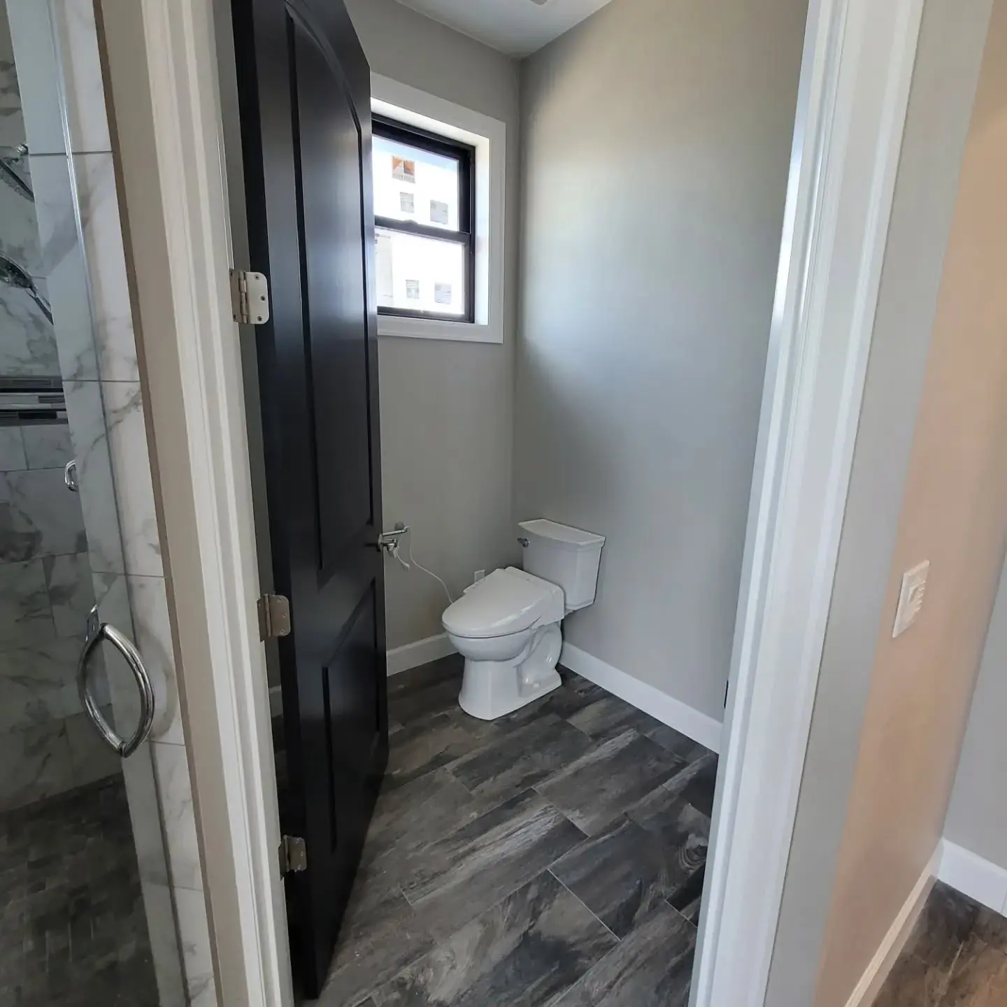 High-contrast bathroom interior with a professionally painted black door and light grey walls.