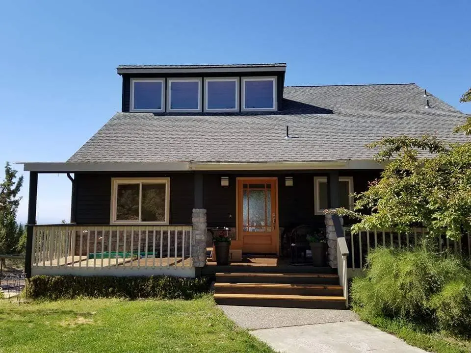 Front view of a Powell Butte home with a new deep charcoal exterior paint scheme and white trim.