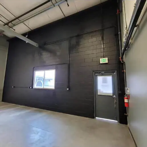 Professional commercial interior painting results showing a seamless black accent wall and grey trim.