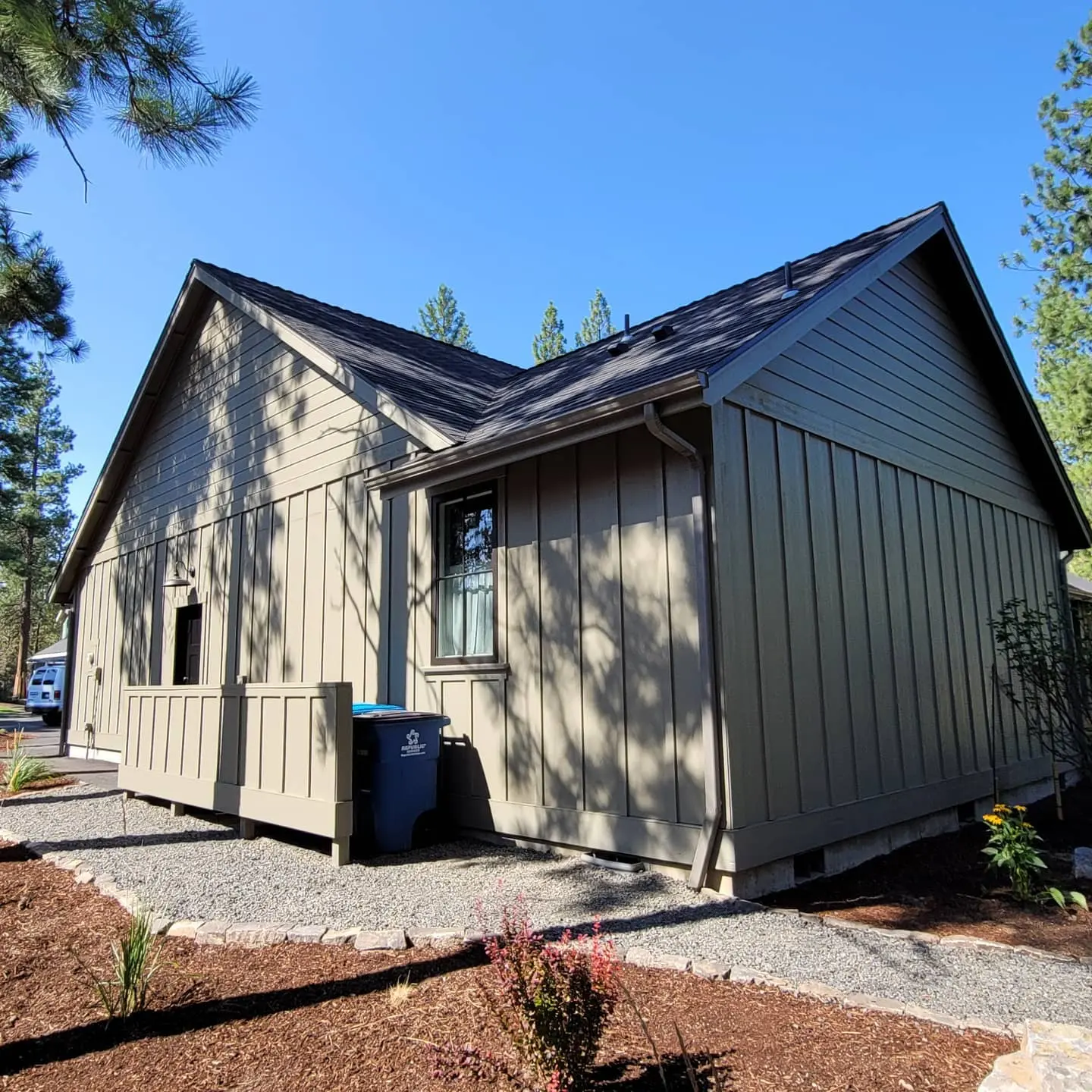 Side angle of a completed house painting project in Sisters, Oregon, blending natural timber with modern sage and black.