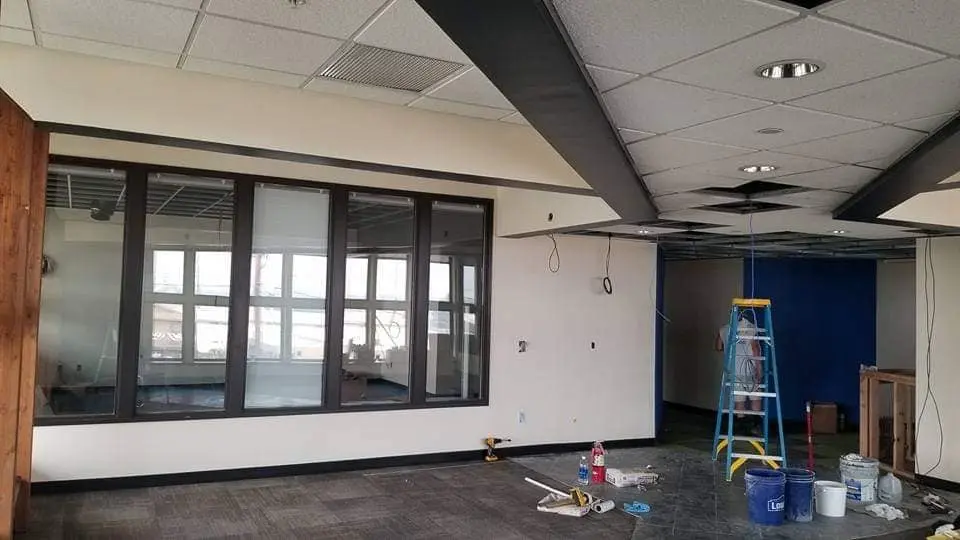 School office area under renovation with painting equipment and a blue accent wall visible in the background