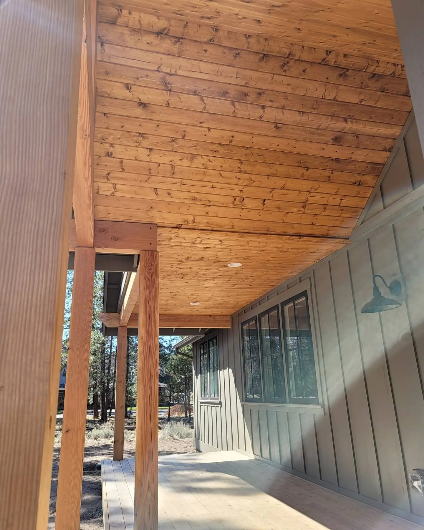 Side view of a Sisters home's outdoor patio featuring vertical board-and-batten siding and a stained wood ceiling.