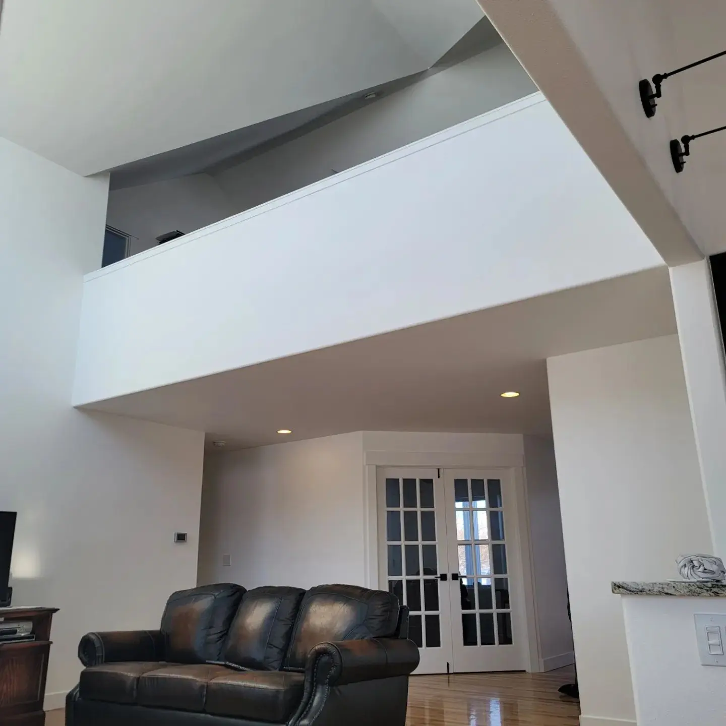 View of a modern home interior in Powell Butte featuring a bright white loft area and dark leather sofa.