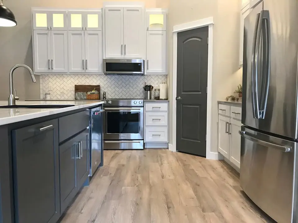 Close-up of a charcoal grey kitchen island with white quartz countertops and a herringbone tile backsplash.
