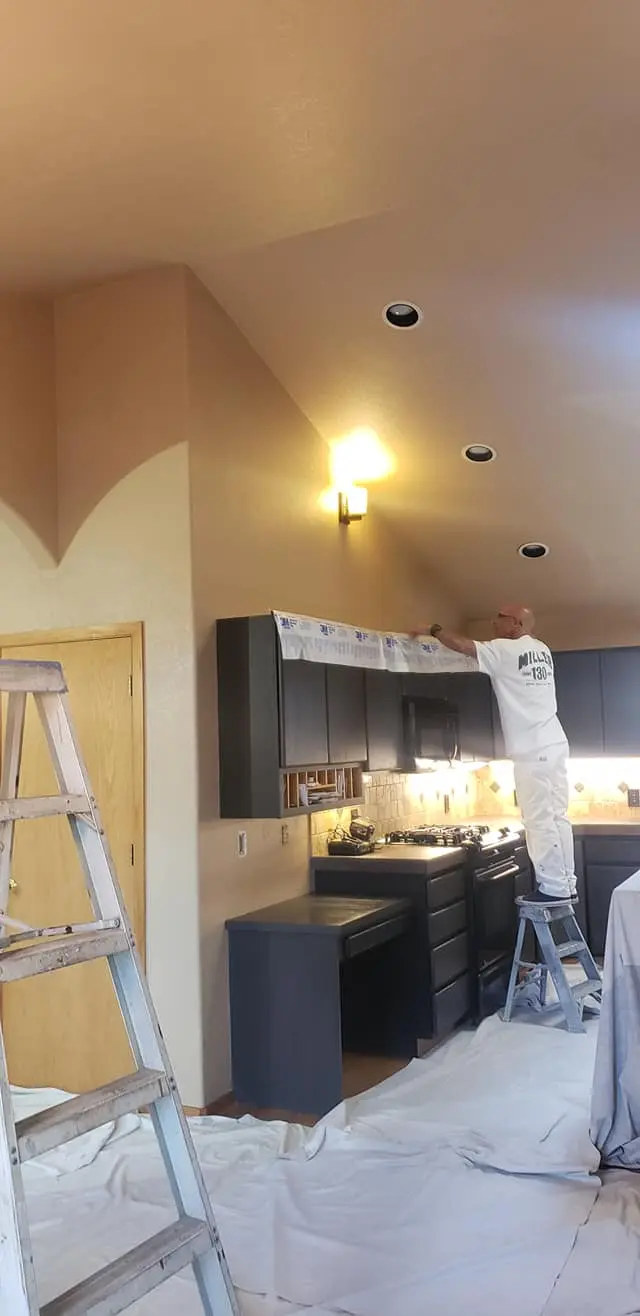 A professional painter carefully masking cabinets before applying paint in a Bend, Oregon home.