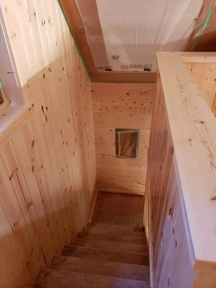 Looking down a pine-clad stairwell showing the uniform texture of natural wood before finishing.