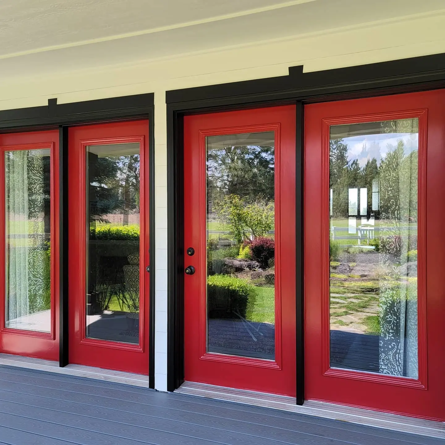 A set of three French doors painted in high-gloss red with black trim on a Bend residential patio.