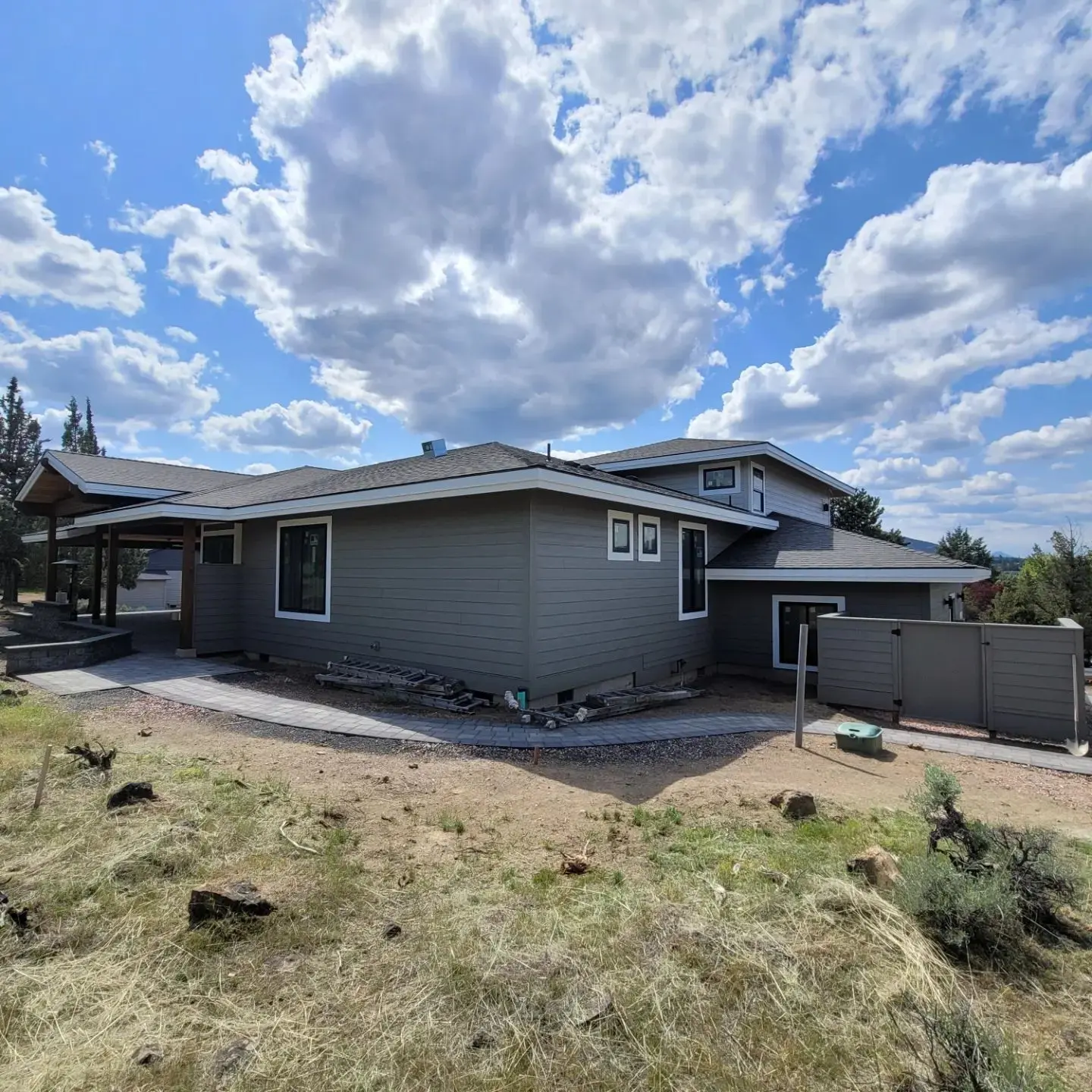 Wide perspective of a modern gray home in Redmond with landscaping in progress and clear blue sky.