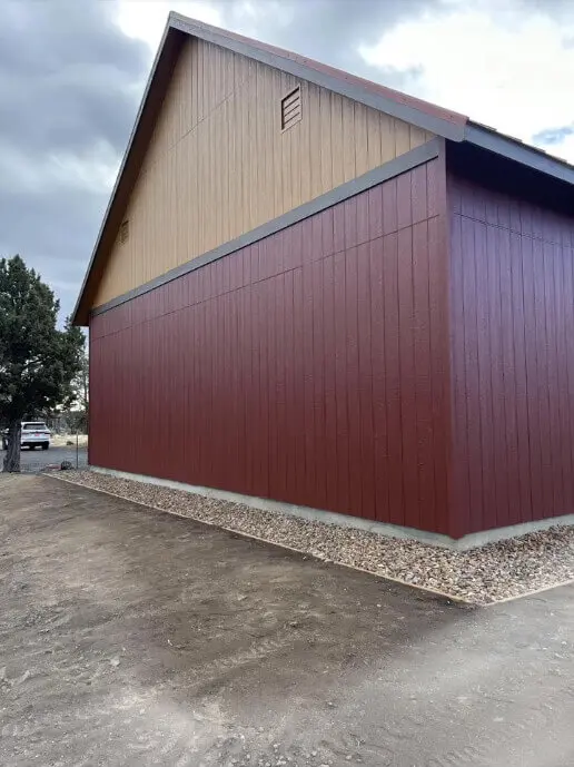 The tan-colored gable end of a large outbuilding professionally painted by local painters.